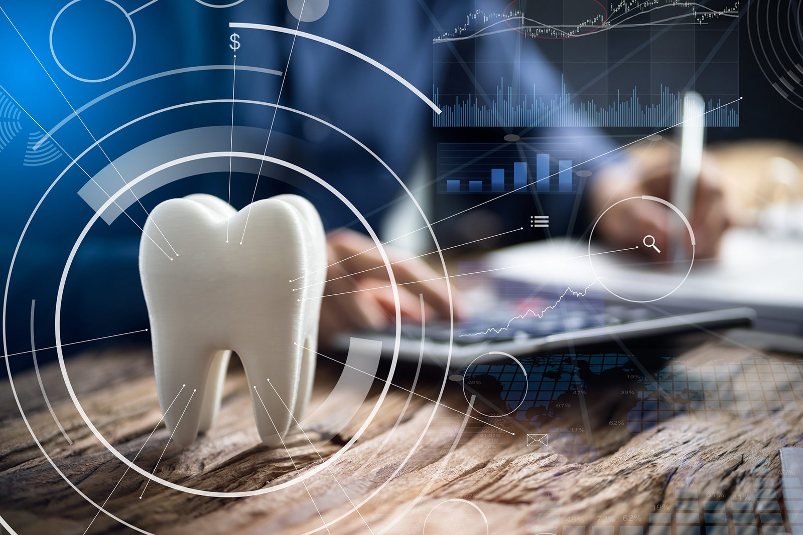 A person writes at a desk near a large tooth model, with overlaid digital graphics of charts and data, suggesting dental technology or business analysis in dentistry.