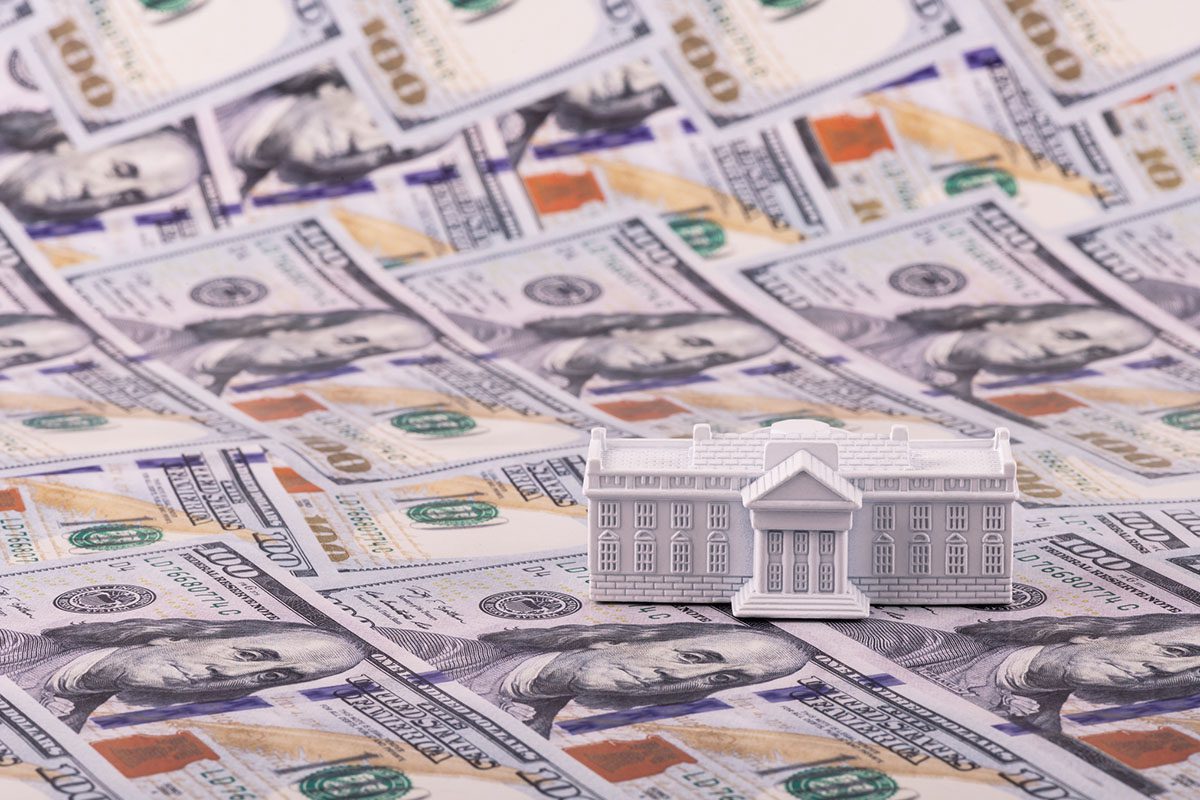 A small model of the White House sits on top of scattered US $100 bills.