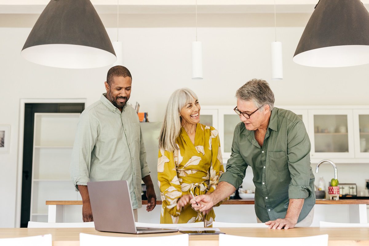 A senior couple sits with a professional, discussing life insurance options. They review documents, focusing on structuring life cover within their financial plan, including ownership, beneficiaries, premiums, and coverage to ensure it meets their long-term needs.