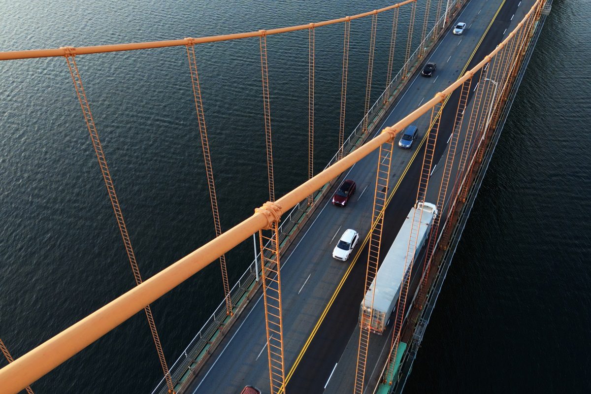 Aerial view of a semi truck crossing a suspension bridge.
