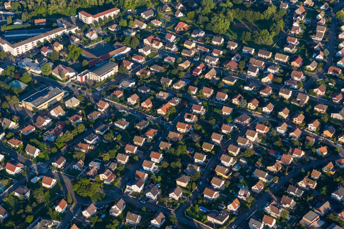 Aerial view of a densely populated residential area with numerous houses and green spaces under natural light