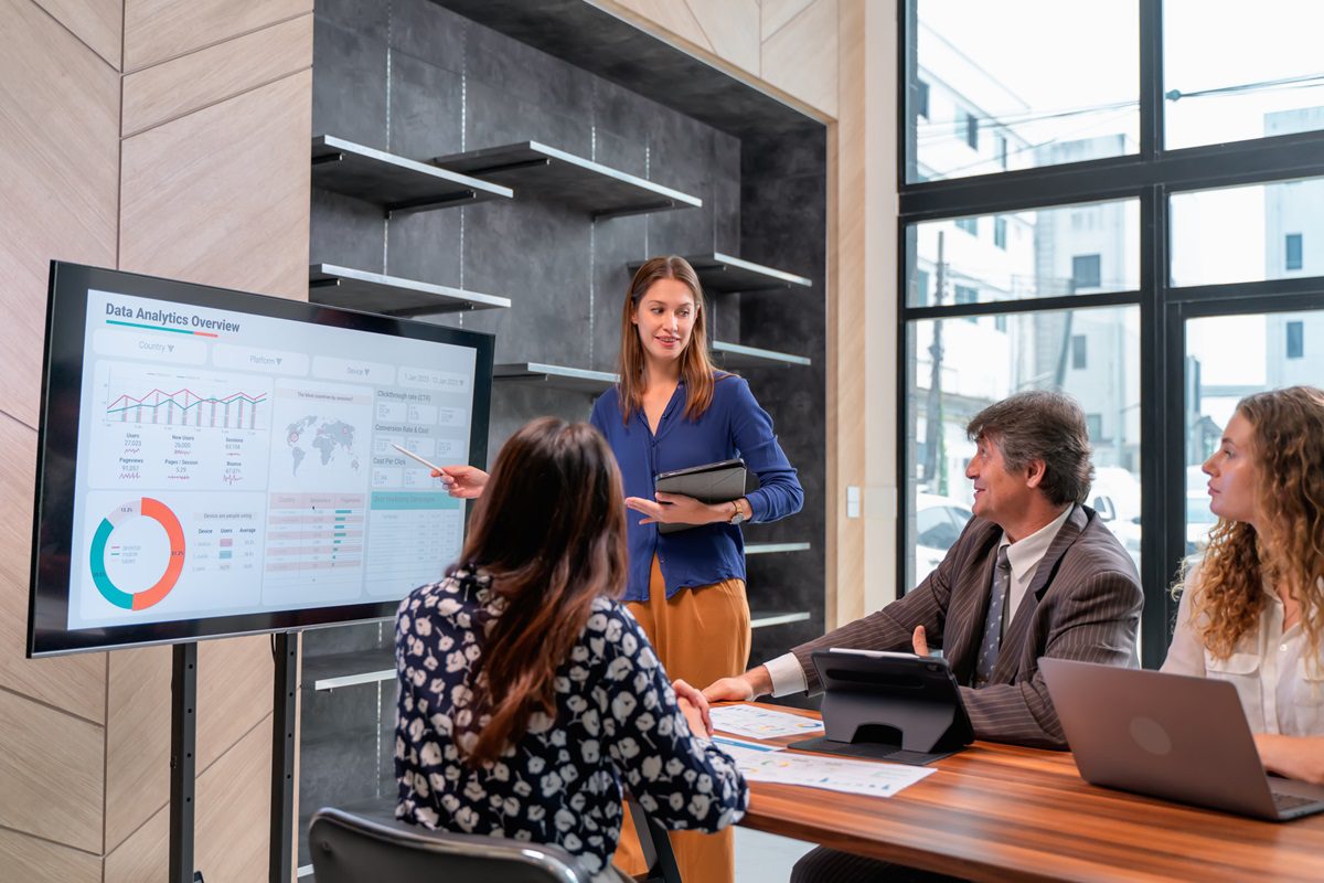 Return on investment (ROI) in businesses evaluates the efficiency of risking their capital. Female Business Development presenting on business plan strategy about a business start-up meeting with her team in the modern office.
