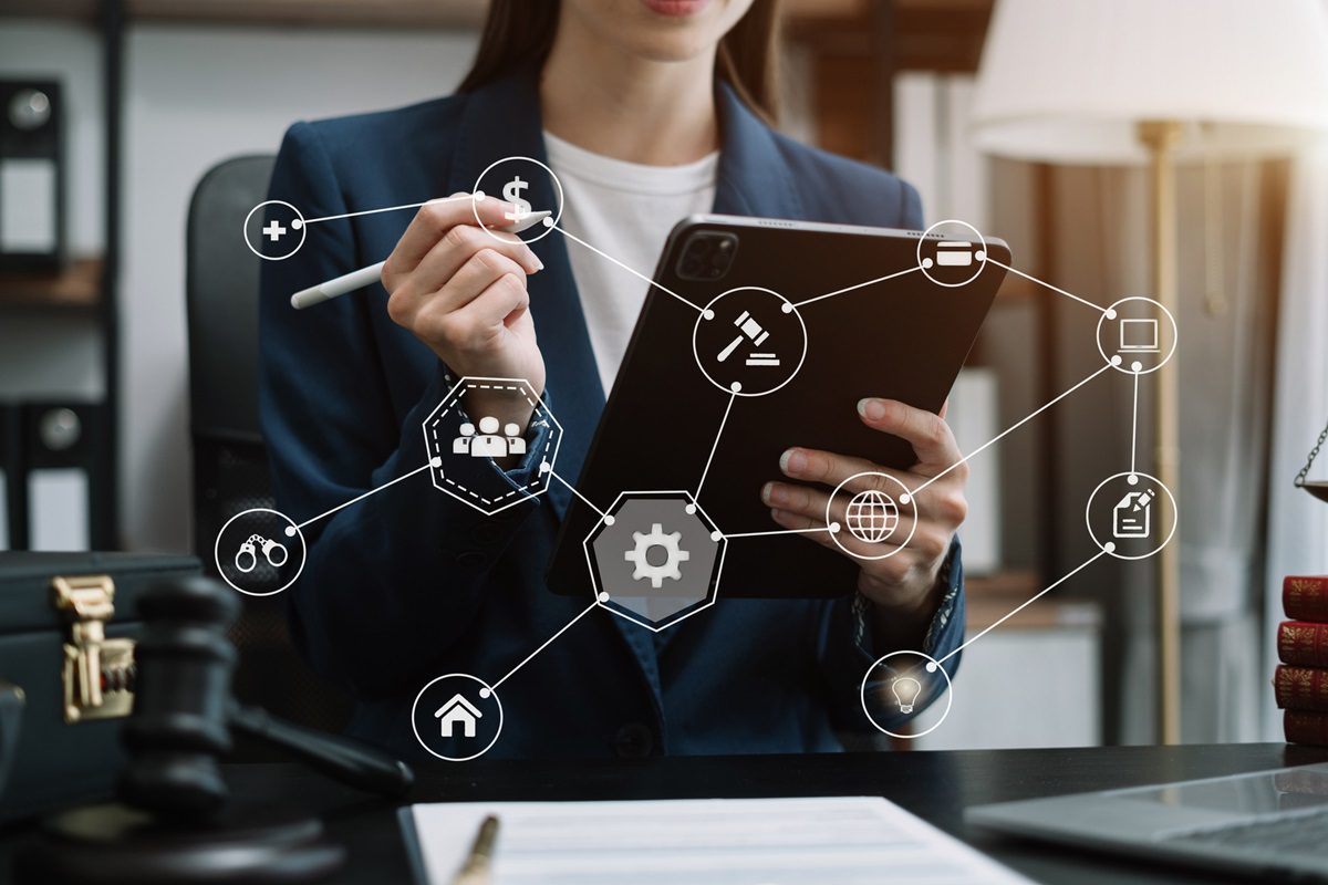 A person in business attire uses a tablet, with digital icons representing various business and legal concepts connected by lines superimposed on the image.