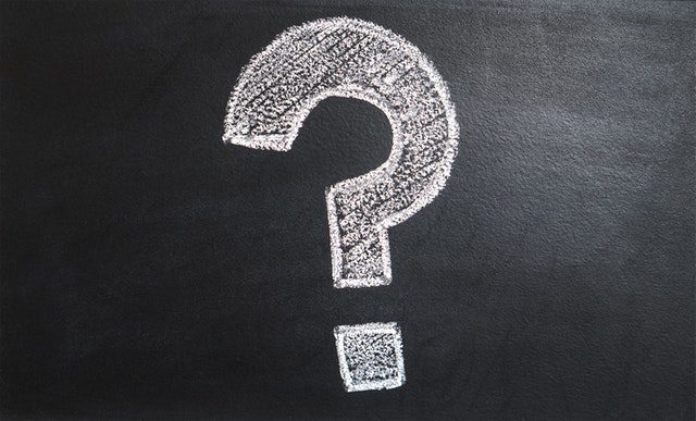 A white question mark is drawn with chalk on a black chalkboard background.