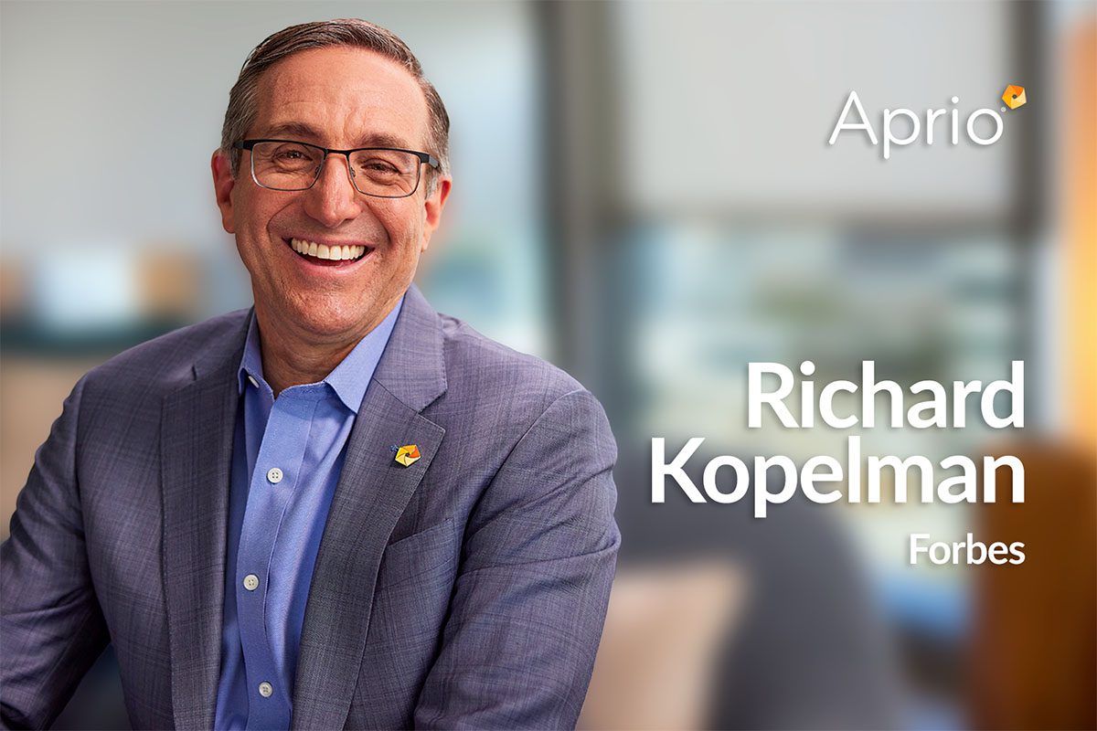 A man in a suit and glasses smiles at the camera; text reads &ldquo;Richard Kopelman Forbes&rdquo; with the Aprio logo in the background.