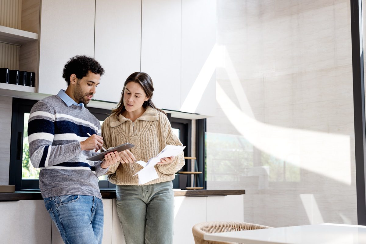 A diverse couple of different ages uses financial software via tablets to invest in funds, manage expenses, and mitigate future financial risks. Home financial, Financial technology.