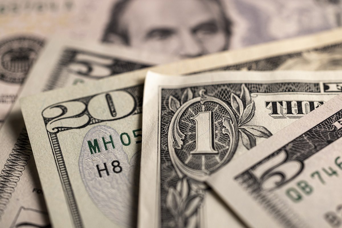Close-up of several US dollar bills, including denominations of one, twenty, and fifty dollars, overlapping each other.