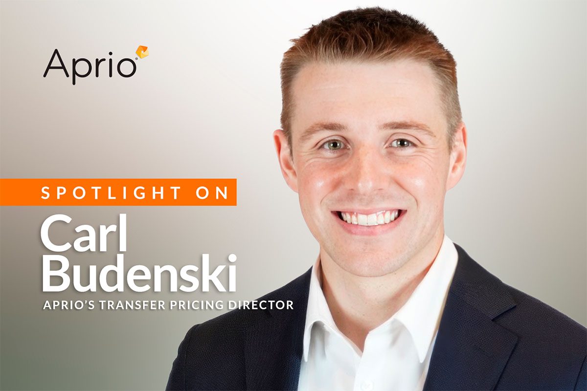 A man in a suit smiles at the camera with text identifying him as Carl Budenski, Aprios Transfer Pricing Director, on a promotional graphic.