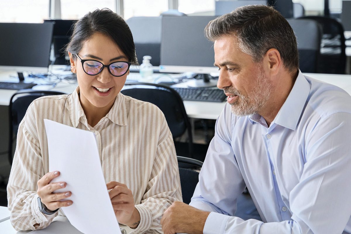 Woman and man in an office having a discussion while holding paperwork