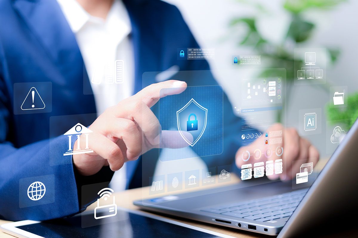 A person in a suit uses a laptop while interacting with virtual security icons, including a digital shield with a padlock, signifying cybersecurity concepts.
