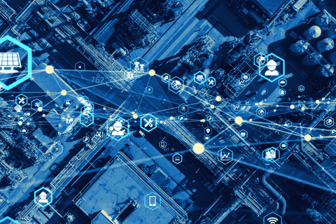 Aerial view of an industrial complex overlaid with digital network icons and lines, illustrating industrial IoT connectivity.