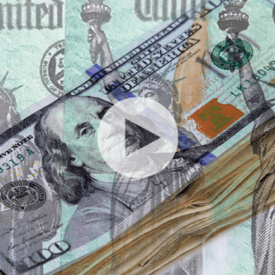 A stack of US $100 bills overlaid with images of the Statue of Liberty and a play button in the center, suggesting a video about money or finance.