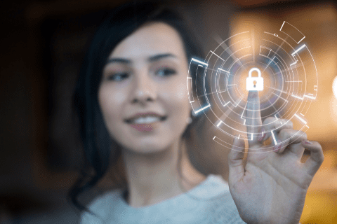 A woman touches a virtual lock icon on a transparent digital interface, representing cybersecurity or data protection.
